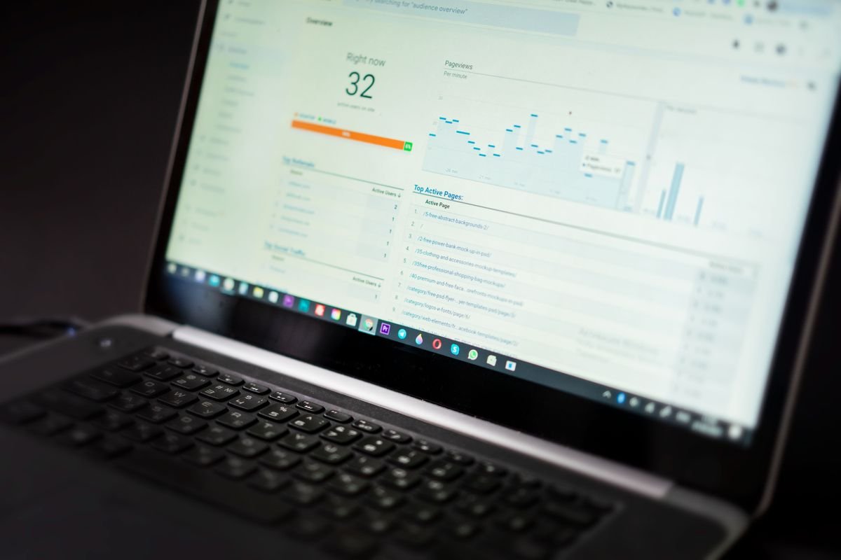 A laptop screen showing an analytics dashboard with charts, on a dark desk